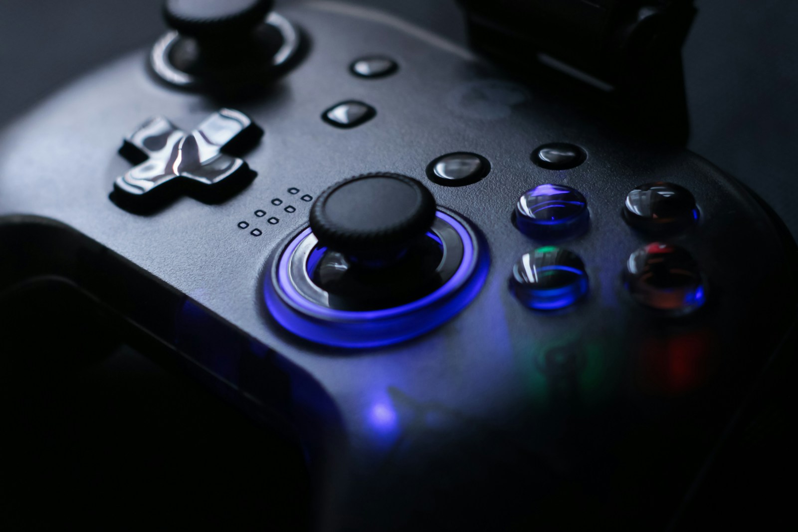 Close-up of a dark video game controller lit with blue light.